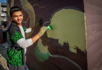 Man participating in the painting of the large sunflower mural at Station Center Family Housing in Union City, Ca.