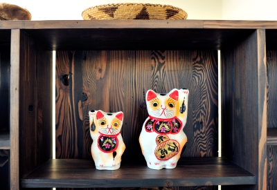 Shelving detal with two  Maneki-neko waving cat figurines at Zero Cottage in San Francisco.
