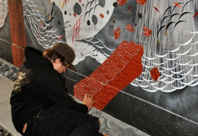 A man, painting his mural at Shotwell Design Lab in San Francisco.