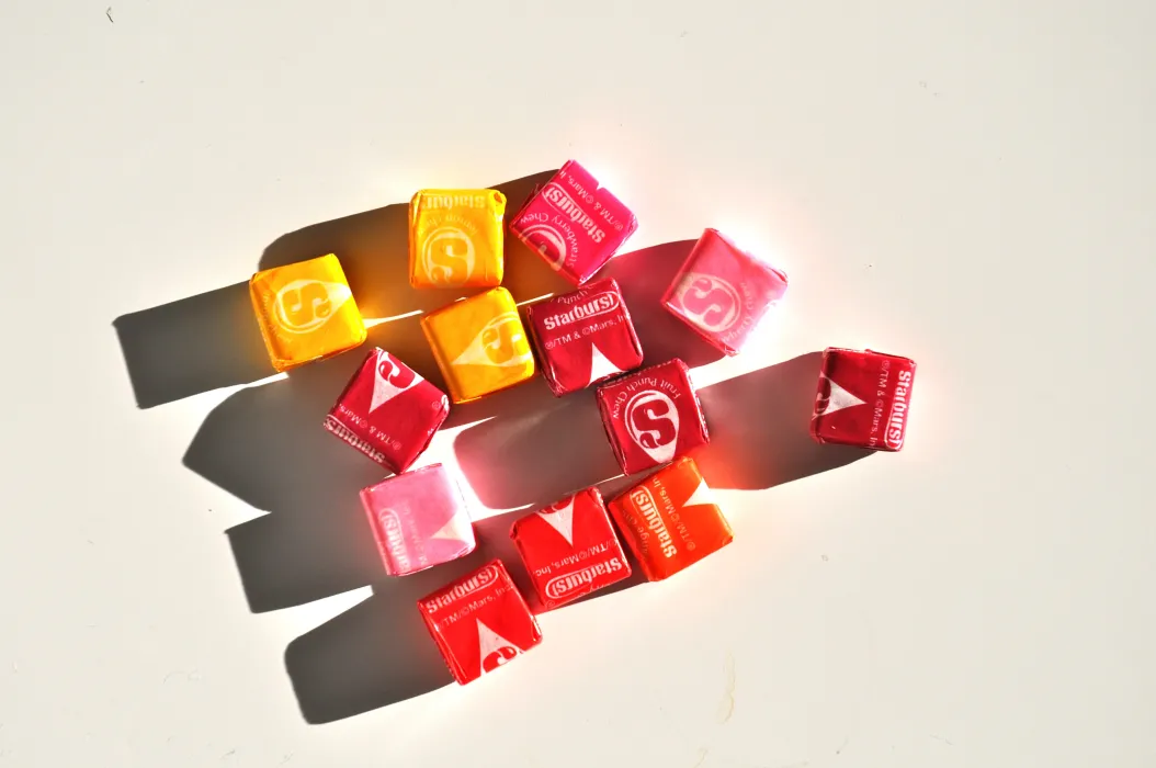Handful of pink, yellow, and red starburst laying on a white background.