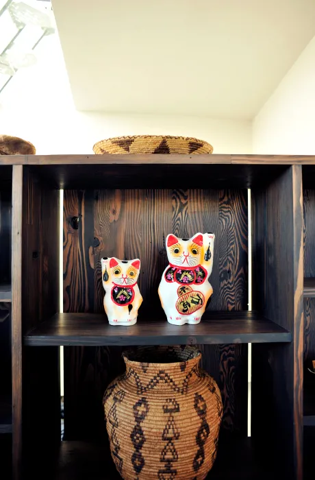 Shelving detal with two  Maneki-neko waving cat figurines at Zero Cottage in San Francisco.