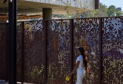 Woman walking her dog next to the weathering steel fence at Blue Oak Landing in Vallejo, California.
