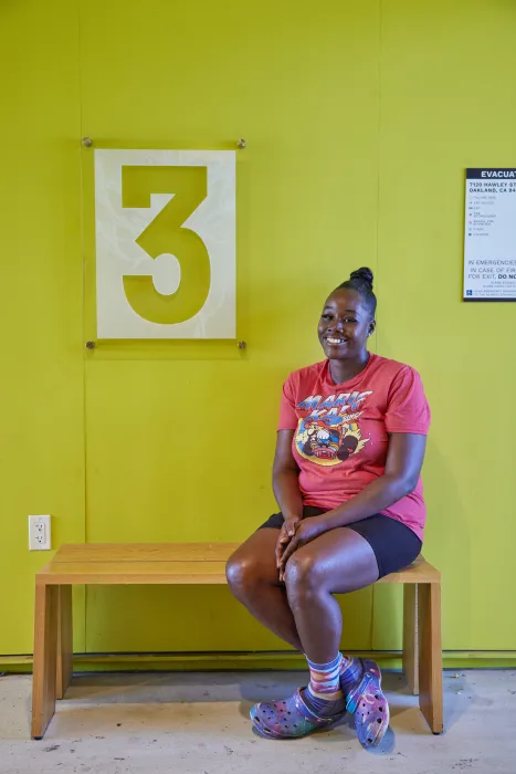 Woman sitting on a bench on the third level of Lobby inside Coliseum Place in Oakland, California.