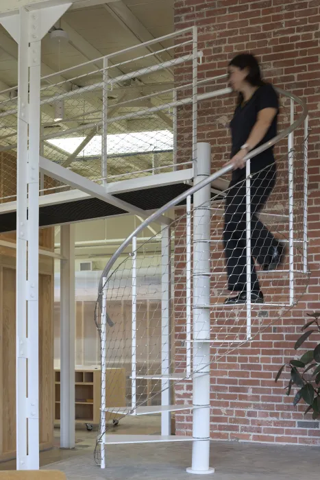 Spiral staircase retrofitted with animal mesh guardrails at Wyatt Builds office.